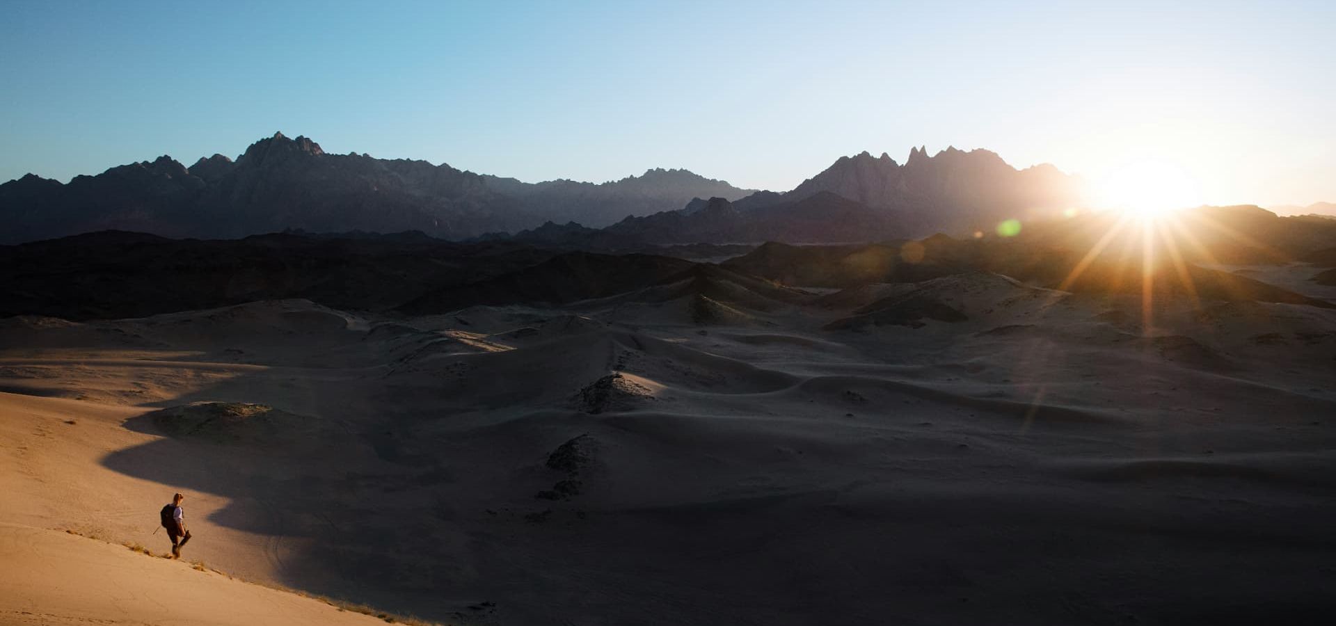 Traveller on desert dunes at sunrise